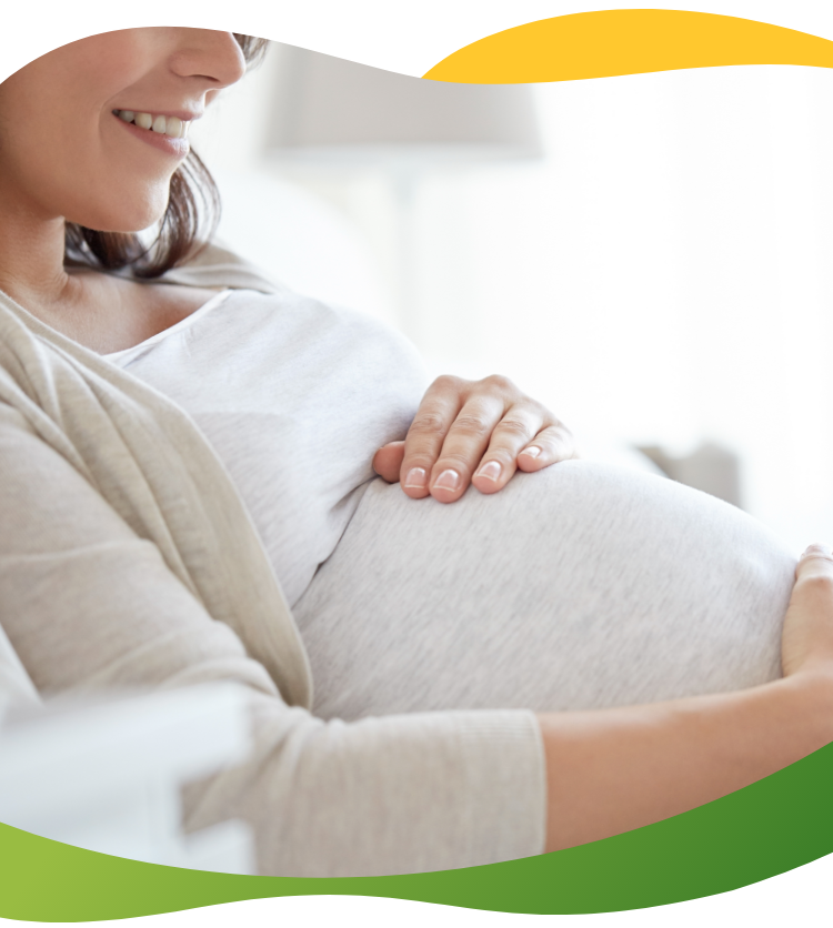 A pregnant woman with no bloating sitting and smiling while stroking her baby belly