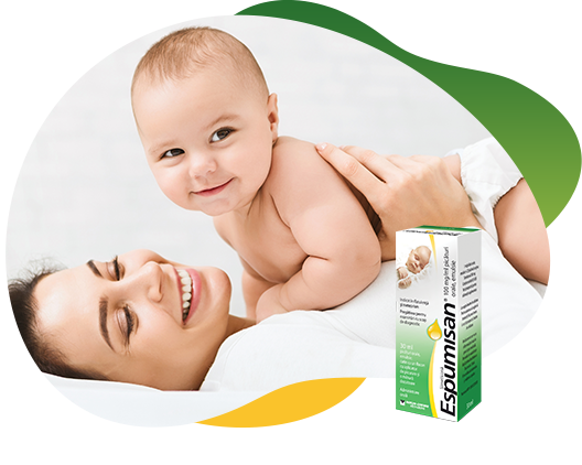 Two packs of Espumisan 100 mg/ml Emulsion in different sizes in the foreground, behind the big package is an illustrated lion. In the background there is a happy baby that lies on his smiling mother and looking curiously at the camera